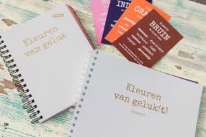 Bruine kaart uit het Kleuren van Geluk-deck naast het boek Kleuren van Geluk en de Bloei! planner – symbolen van aarden, stabiliteit en nieuwe tradities in de kleurpsychologie
