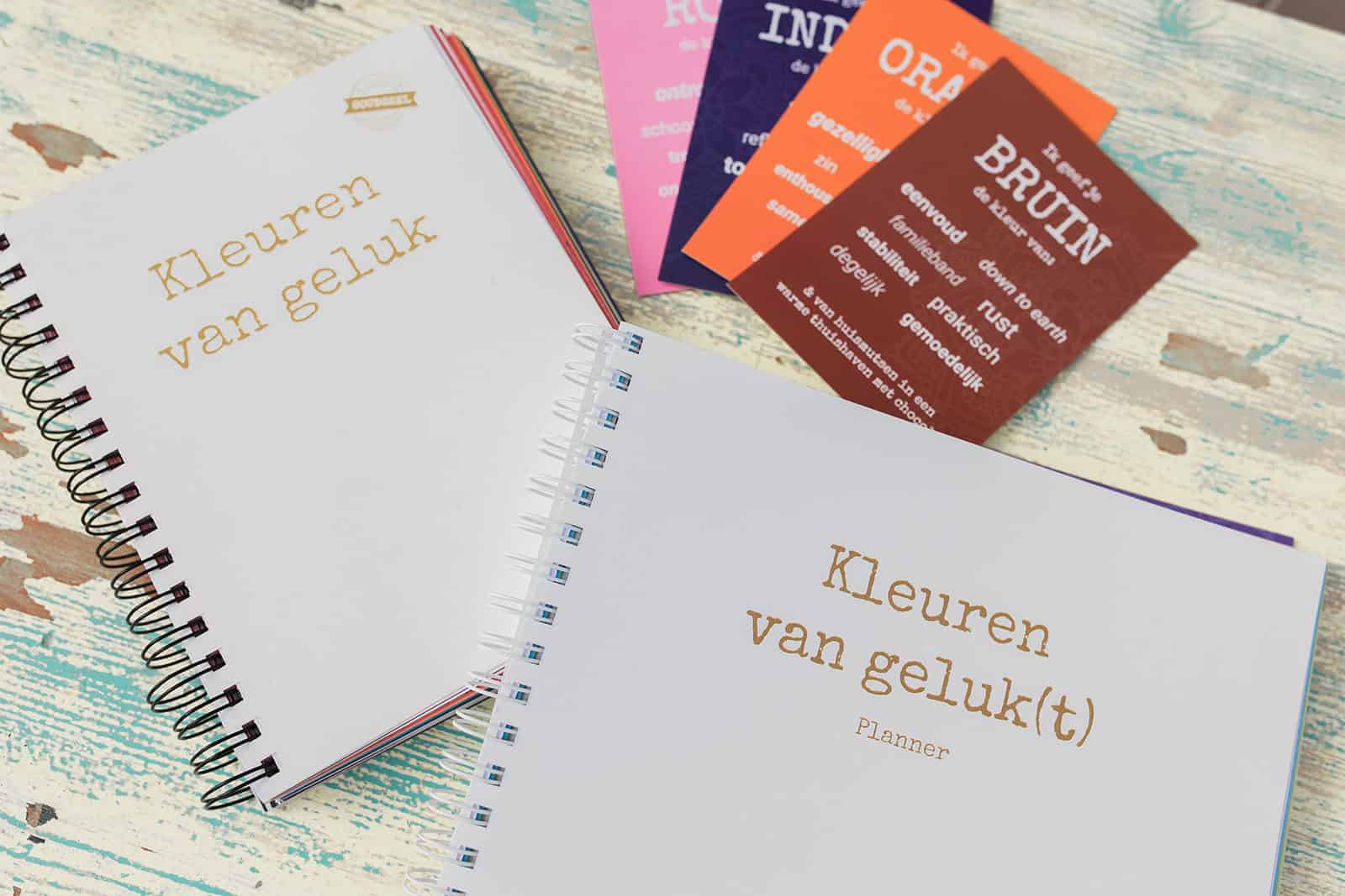 Bruine kaart uit het Kleuren van Geluk-deck naast het boek Kleuren van Geluk en de Bloei! planner – symbolen van aarden, stabiliteit en nieuwe tradities in de kleurpsychologie