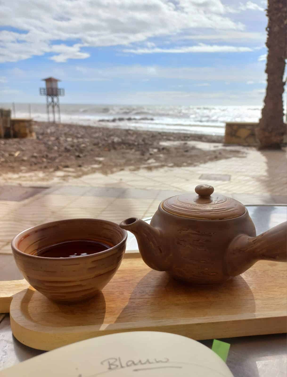 Blauwe lucht en zee met kopje thee en schrijfboek – reflectie op de kleur blauw